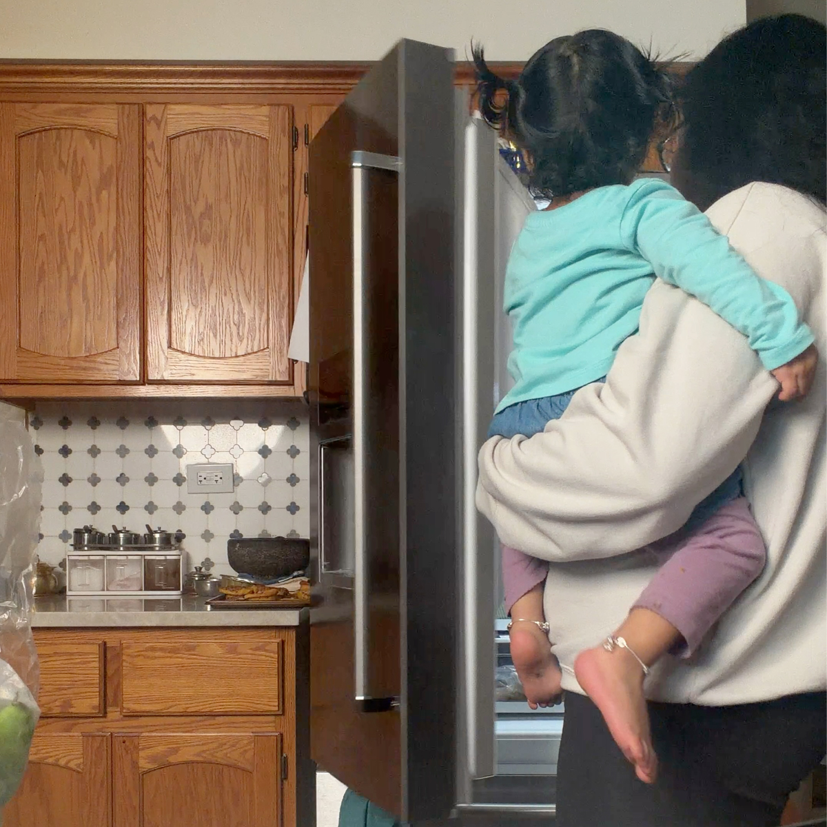 abhi holding her toddler looking into the fridge