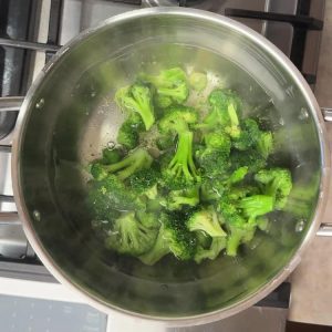 Bright green broccoli florets blanching in boiling water in stainless steel pot