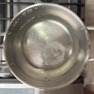 Salted water beginning to boil in a stainless steel pot on gas stovetop