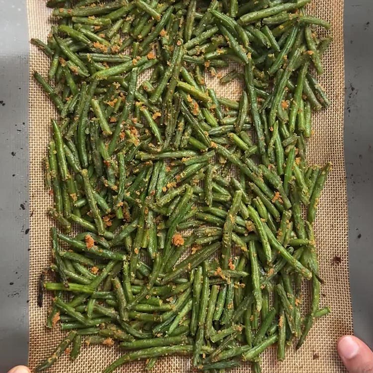 Crispy oven roasted green beans coated with coconut garlic podi on a sheet pan, ready to serve