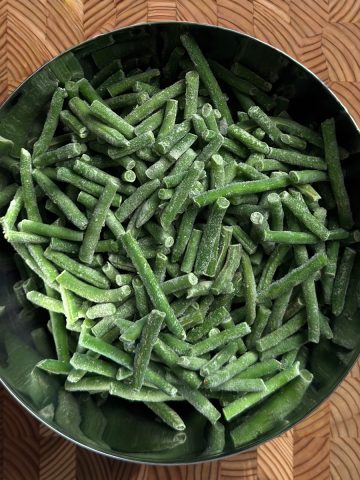 frozen green beans in a bowl on a custting board