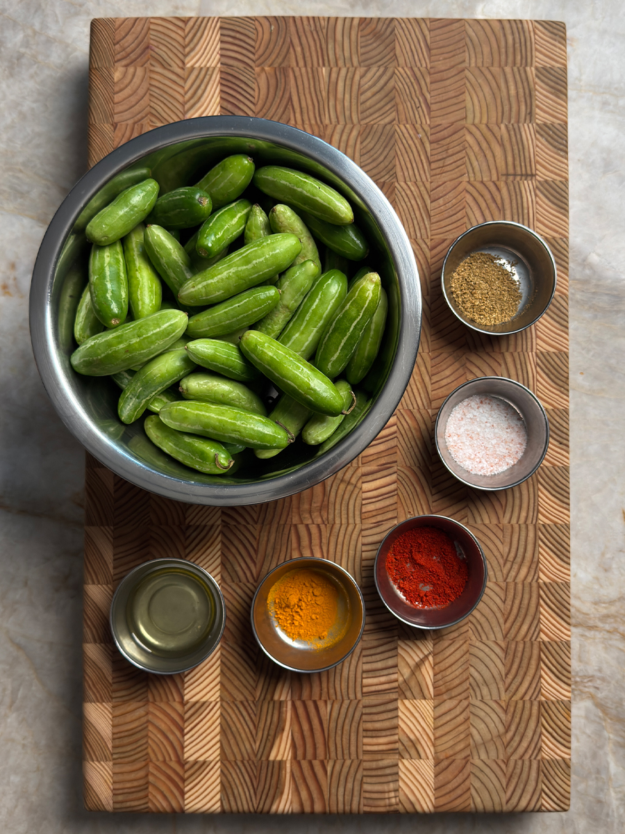 Fresh dondakaya (ivy gourd) in a bowl with turmeric, chili powder, coriander, salt, and oil