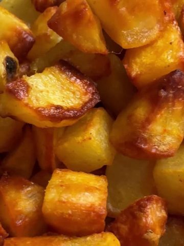 Close up of crispy oven roasted potatoes showing golden brown edges and tender centers