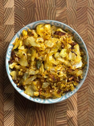 Oven roasted cabbage fry with golden turmeric color and crispy edges in a decorative bowl
