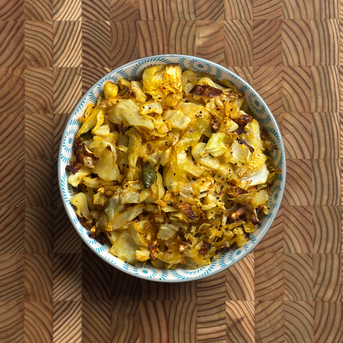 Oven roasted cabbage fry with golden turmeric color and crispy edges in a decorative bowl