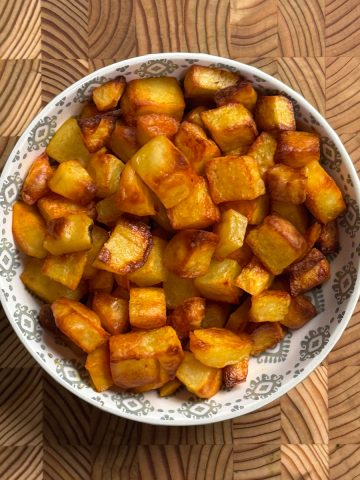 Oven roasted potatoes served in a white bowl, golden brown and crispy cubes