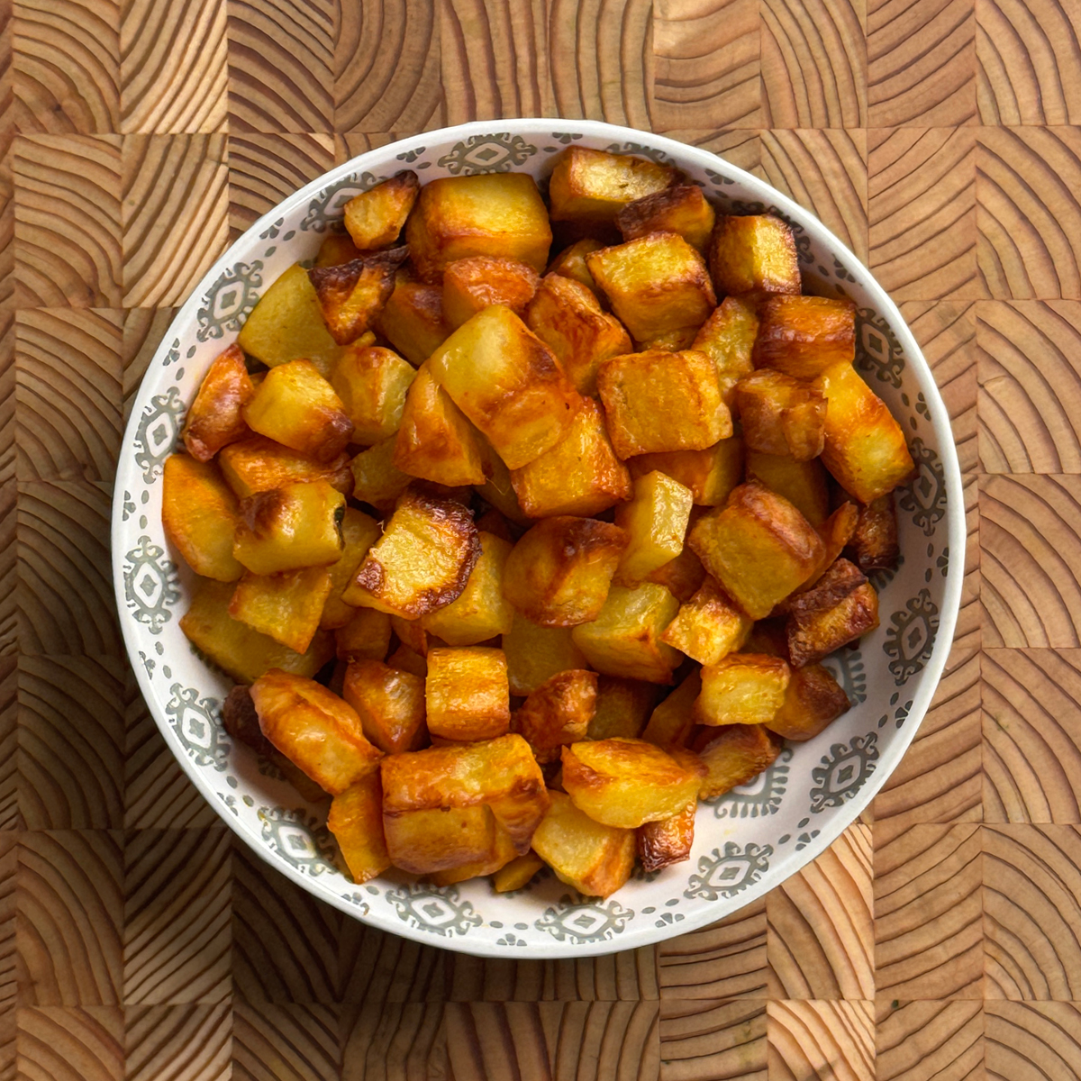 Oven roasted potatoes served in a white bowl, golden brown and crispy cubes