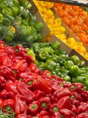variety of bell peppers laid next to each other in a grocery store.