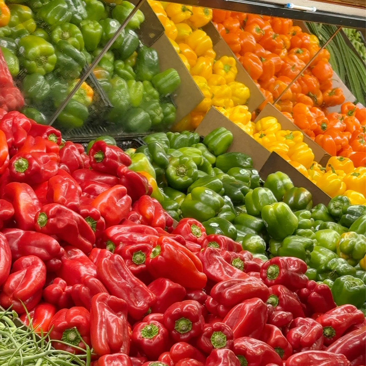 variety of bell peppers laid next to each other in a grocery store.