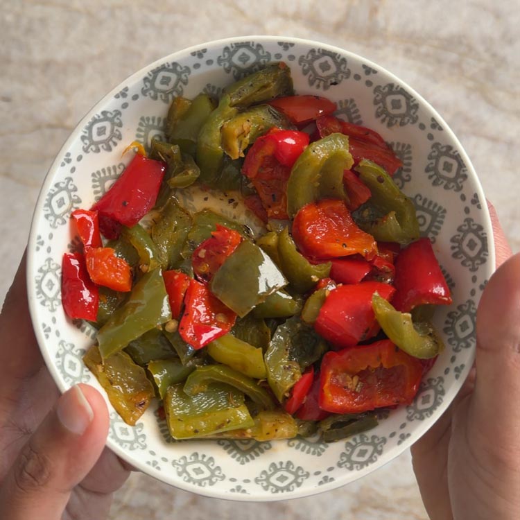 Reheated roasted peppers from frozen in a bowl with some liquid released after microwaving