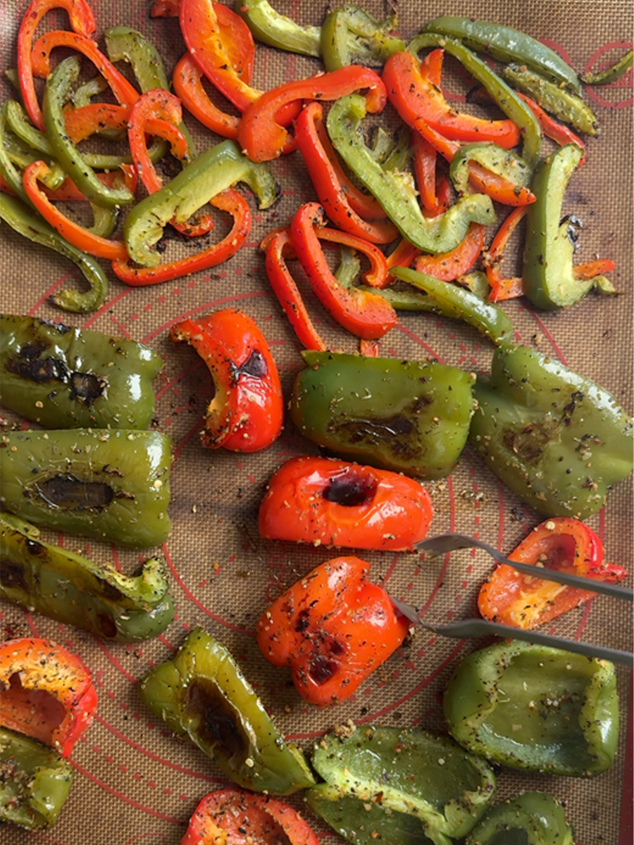 Three cut styles of roasted peppers on a baking sheet: strips, wedges, and square chunks