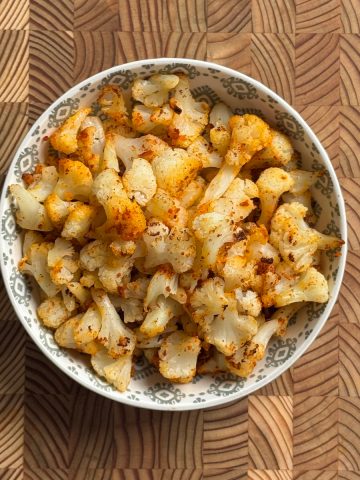 Baked frozen cauliflower with garlic chili powder served in a patterned bowl, overhead view