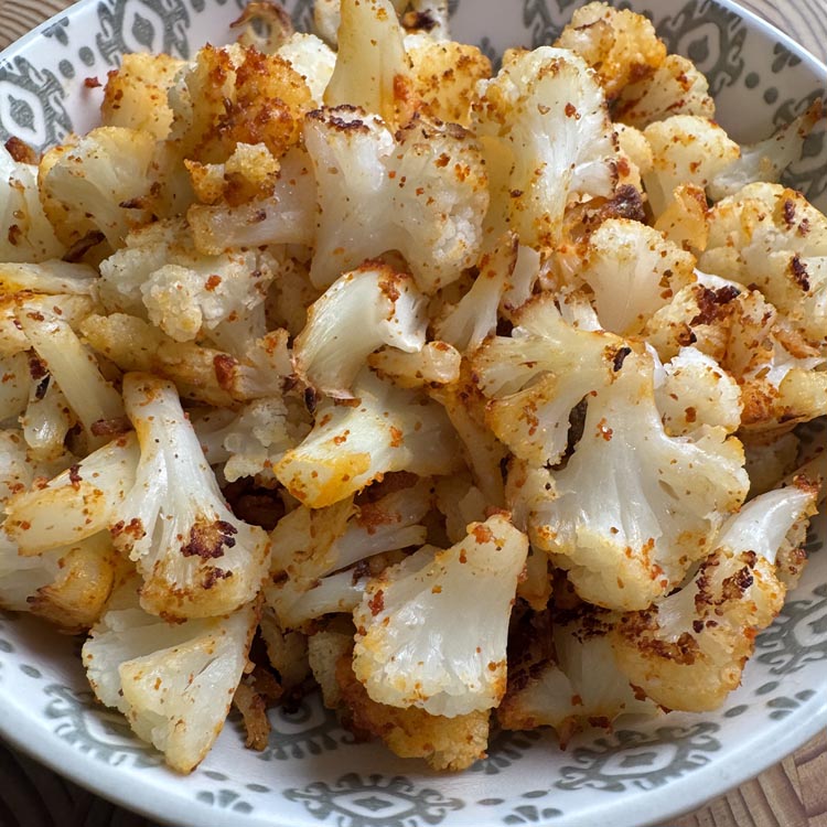 Crispy baked frozen cauliflower with garlic chili seasoning served in a decorative bowl, close up