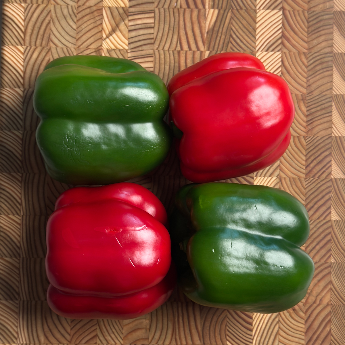 green and red bell peppers on a wooden cutting board