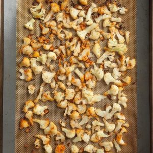 Golden roasted cauliflower florets with charred edges on a sheet pan after 30 minutes at 425F