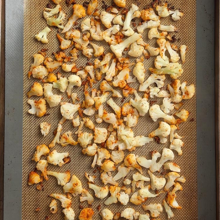 Golden roasted cauliflower florets with charred edges on a sheet pan after 30 minutes at 425F