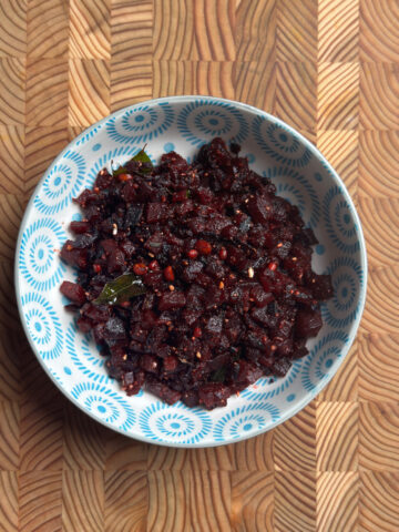 Andhra beetroot fry served in a blue patterned bowl on a wooden cutting board, overhead view
