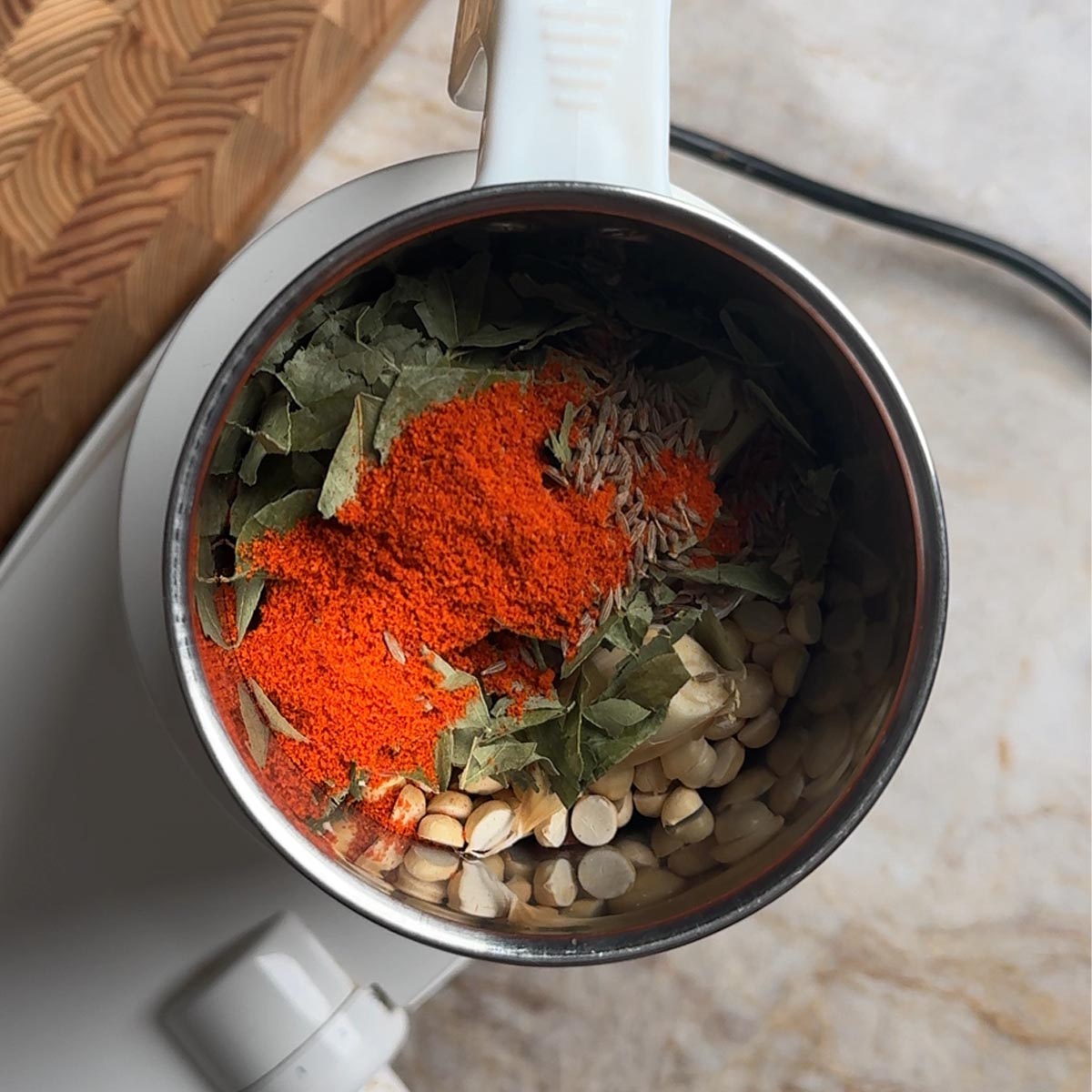 roasted peanuts, chana dal, curry leaves, chili powder, cumin seeds, and garlic in a mixer grinder jar