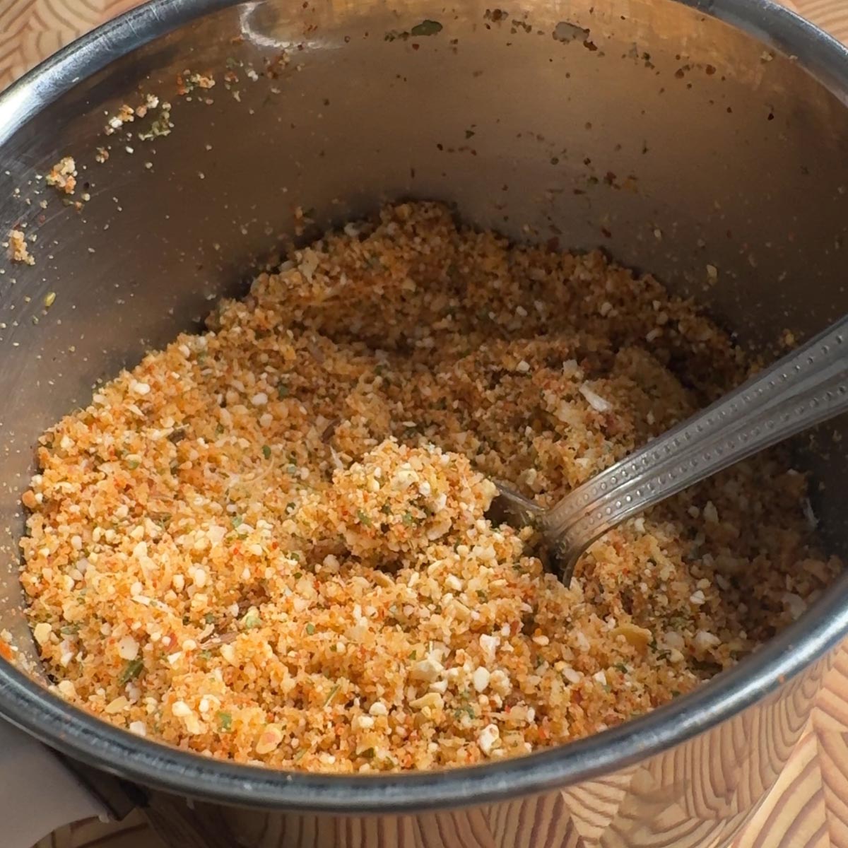 coarse spice powder in a steel bowl with a spoon, showing the texture of the ground peanuts and chana dal