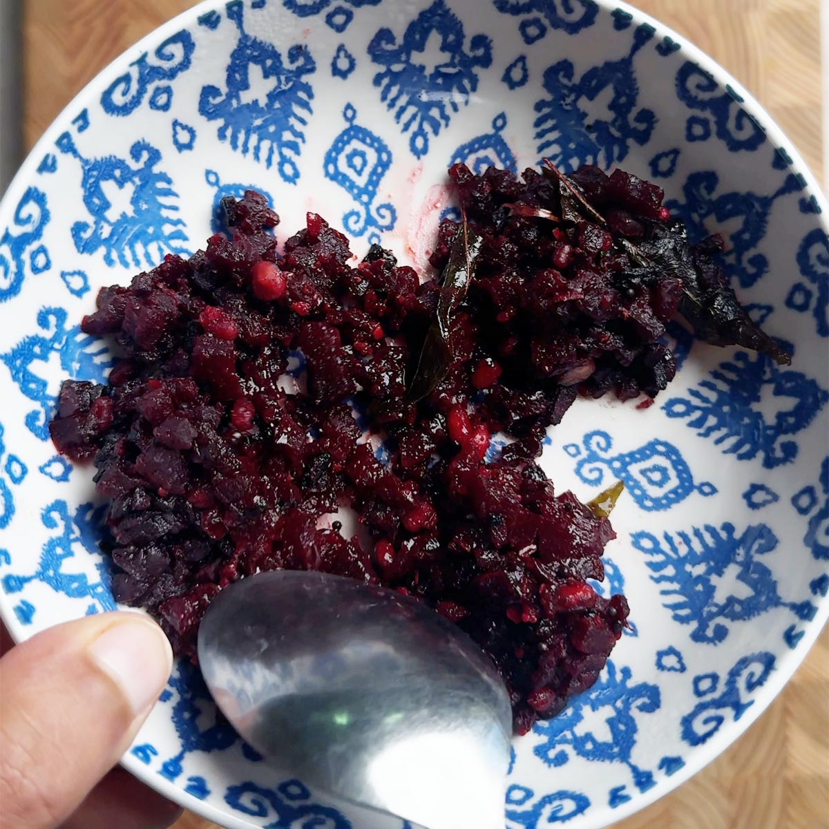 Andhra beetroot fry just microwaved straight from frozen in a blue bowl, broken apart with a spoon