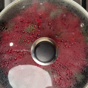 Glass lid with steam condensation over cooking beetroot, showing the lid steam method