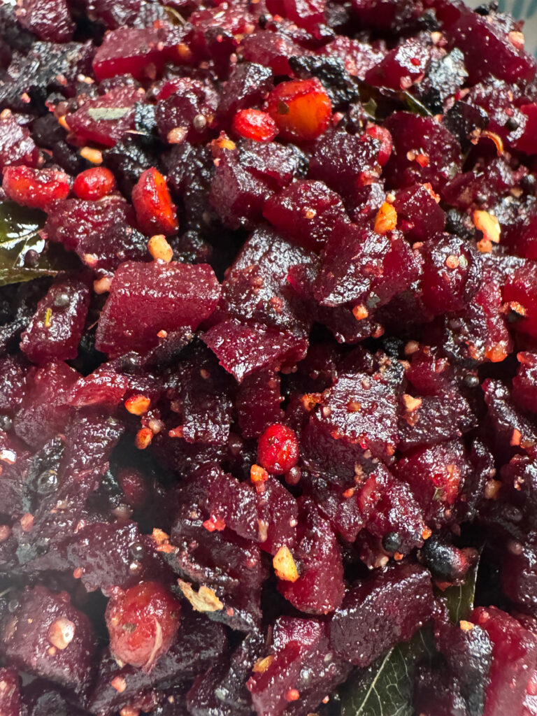 Close up of cooked beetroot fry showing small diced texture with mustard seeds and red chili flakes