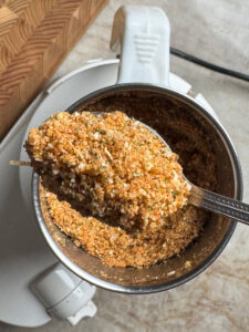 freshly ground coarse spice powder in a mixer grinder jar with a spoon