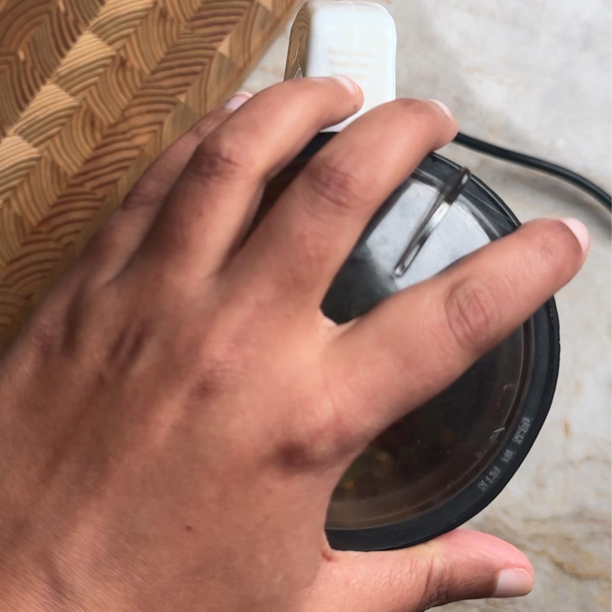 hand pressing the lid of a mixer grinder to grind spice powder