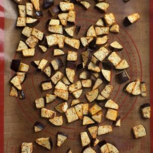 Golden roasted eggplant cubes on a silicone mat after 20 minutes at 425 degrees F