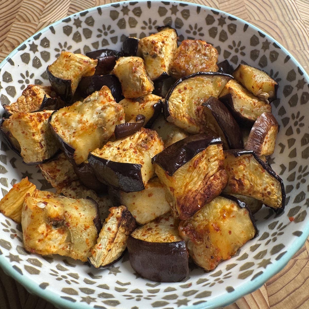 Oven roasted eggplant cubes with golden edges and tender interior in a serving bowl