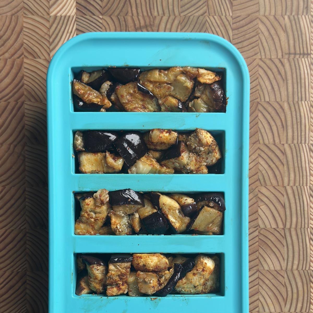 Roasted eggplant portioned into a teal Souper Cubes silicone tray for freezer meal prep