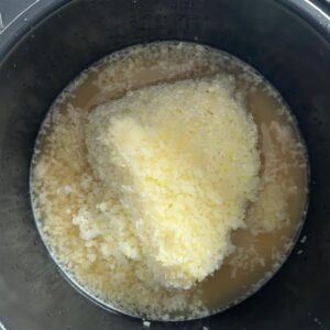 Frozen riced cauliflower added on top of rice and broth in the pot