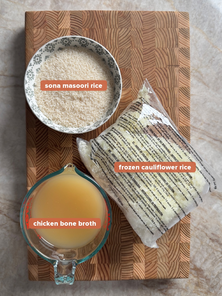 Rice, chicken bone broth, and frozen cauliflower rice labeled ingredients on a wood board