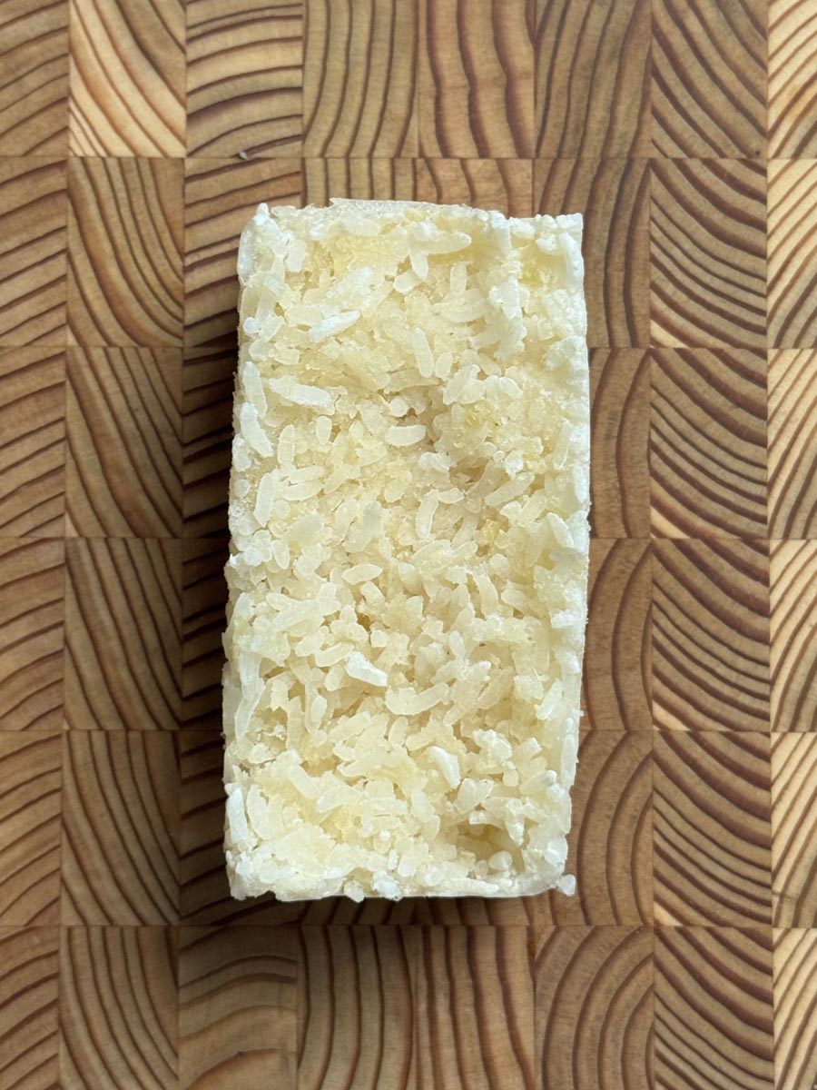 Close up of a single frozen cauliflower rice with bone broth block, ready to reheat