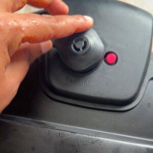 Finger closing the pressure cooker venting valve before cooking