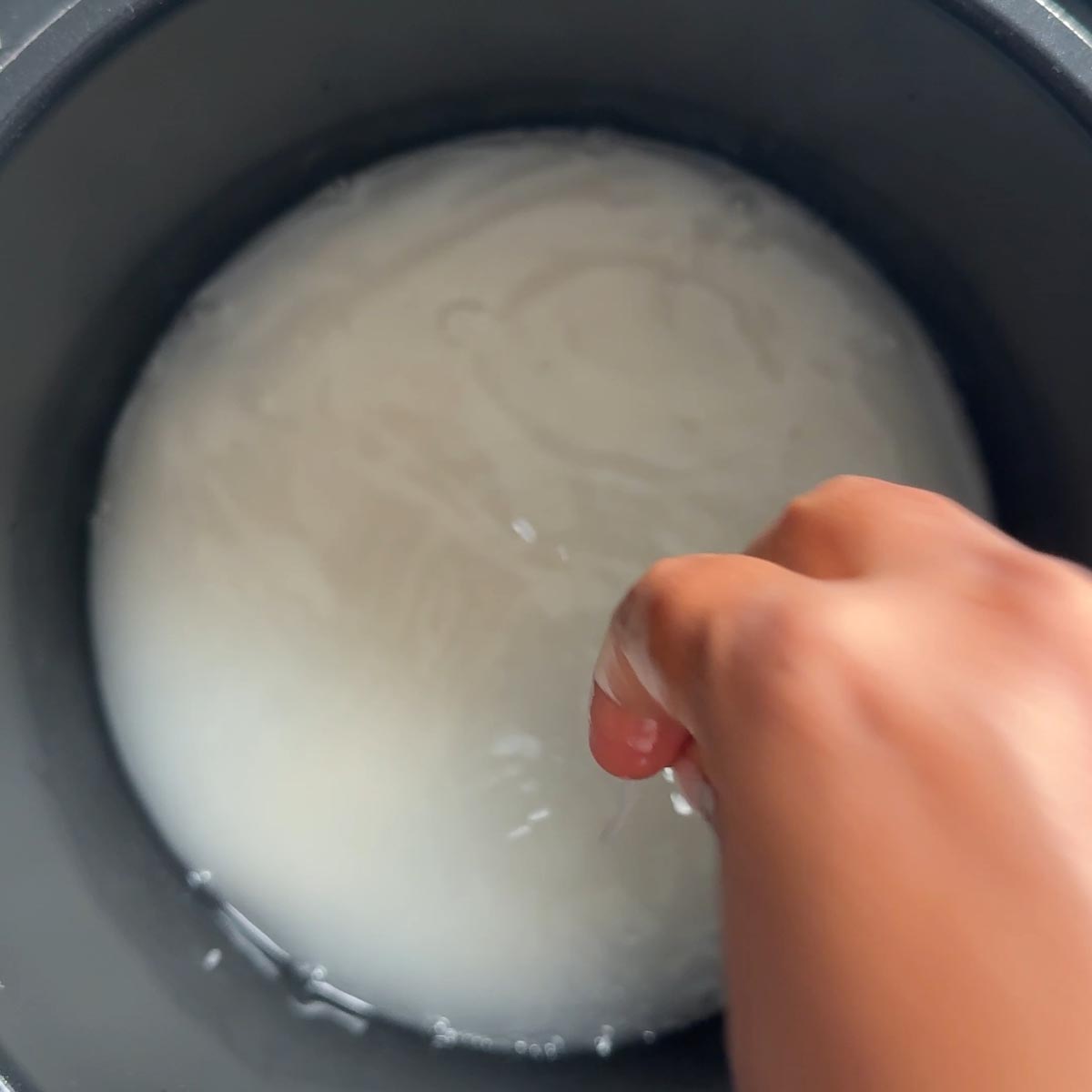 Hand rinsing rice under running water in a fine mesh strainer