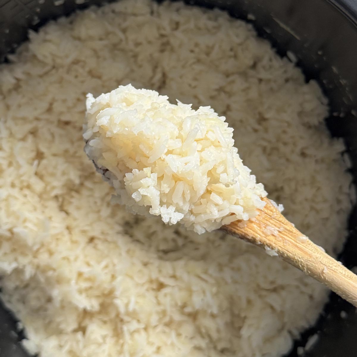 Spoon lifting a scoop of fluffy cooked rice and cauliflower rice blend