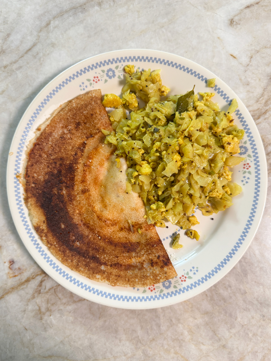 A folded dosa served with cabbage paneer bhurji on the side