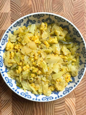 A bowl of cabbage paneer bhurji, a bright yellow scramble flecked with mustard seeds and curry leaves.